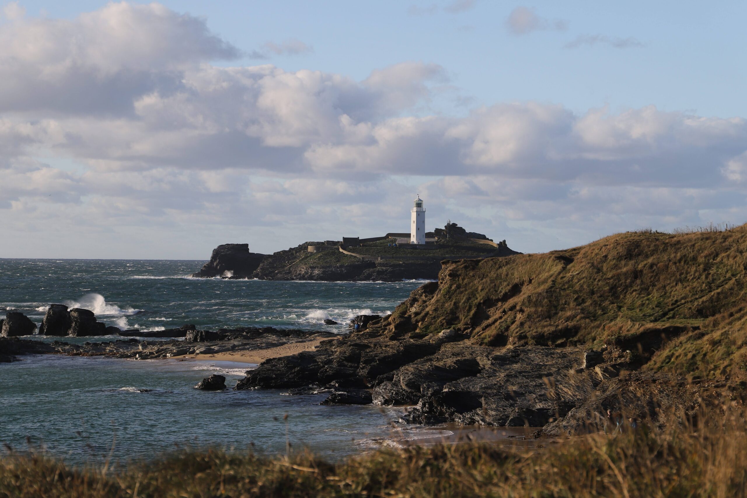 Godrevy Lighthouse im Abendlicht. Davor die felsige Küste. 