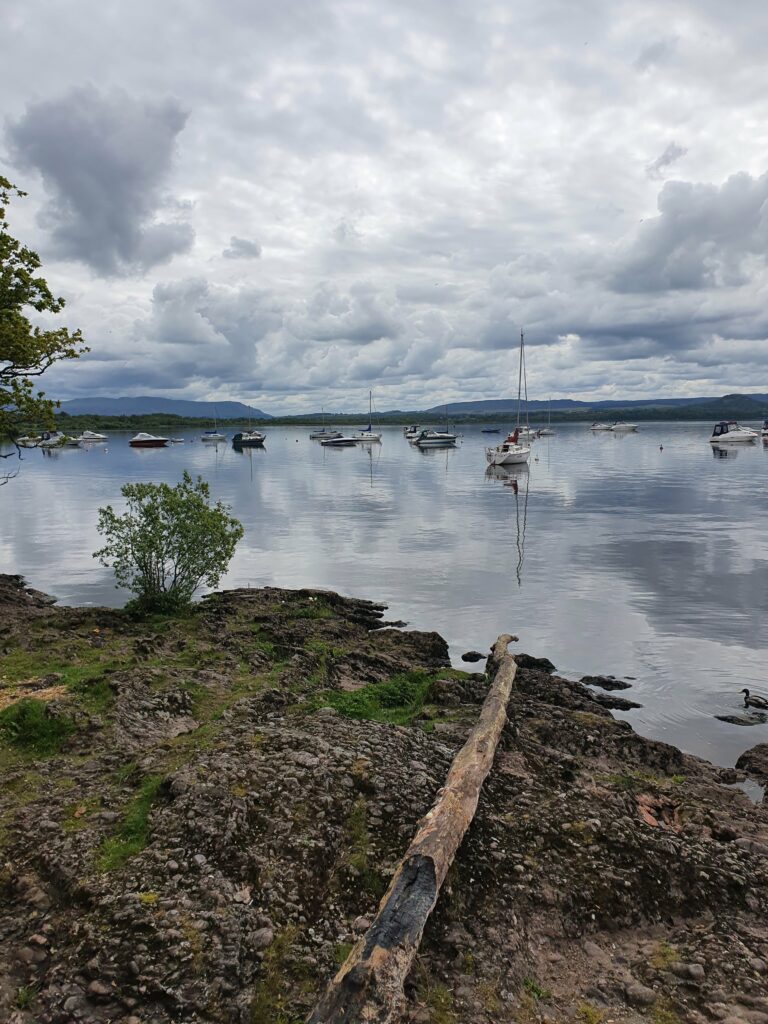 View over Loch Lomond. The sky is cloudy. Boats are floating in the water.
